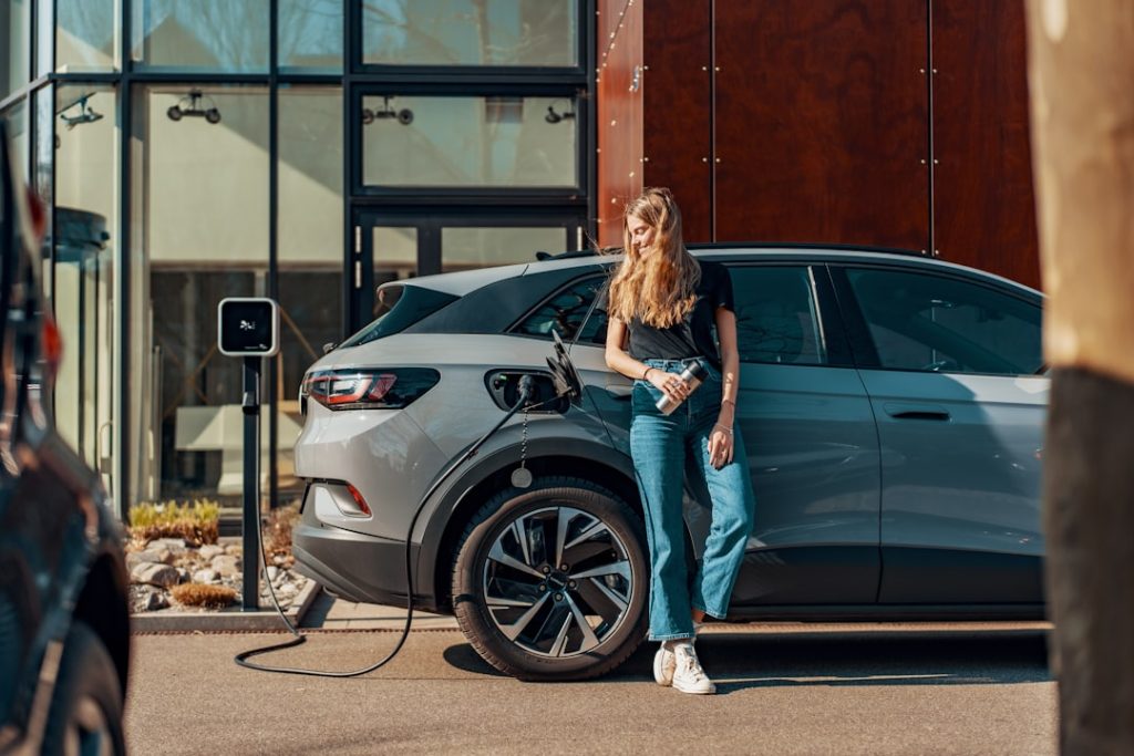 a woman standing next to a blue car a woman standing next to a blue car