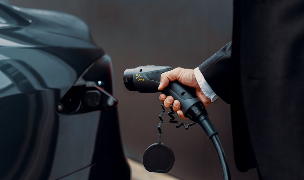 a man in a suit is pumping gas into a car a man in a suit is pumping gas into a car